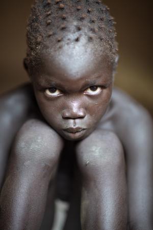 Young child facing the camera, his chin in his laps