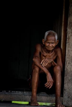 Old man parefoot in front of his house