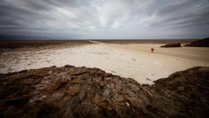 Small red person walking alone in a desert